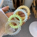 Close-up of four spiral telephone wire hair ties in solid yellow and spotted patterns - Yellow Mango Pomelo Style