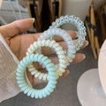 Close-up of four spiral hair ties in mint green, cream floral, and transparent shades - Green Grape Milk Style