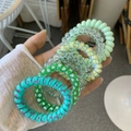 Close-up of colorful spiral telephone cord hair ties in various patterns and colors - Green Mint Coconut Style