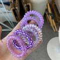Close-up of flexible spiral telephone wire hair ties with star patterns and sequins - Purple Blueberry Style