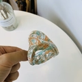 Elegante pinza para el cabello de acetato con patrón de mármol colorido sostenida en la mano - Floral Verde