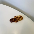Close-up of irregular amber hair clip with handmade engraving on acetate surface - Caramel color