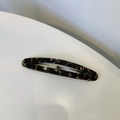 Dettaglio macro di fermaglio per capelli in acetato con trama marmorizzata marrone - Marmo Nero Oro