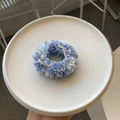 Detailansicht eines blau-weißen plissierten Haargummis im Boho-Stil auf weißem Teller - Blauweiß Panna Cotta (Feines Netz)
