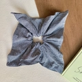 Detailed close-up of blue and white gingham large hair scrunchie on wooden background - Grey Grid