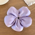 Vue détaillée d'un chouchou fleur en satin violet sur une table en bois rustique - Violet