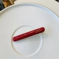 Macro detail of glossy red duckbill hair clip featuring golden Barrette la France text - Red