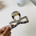 Close-up of leopard print bow hair claw with gold spring mechanism held in hand - Transparent Black - Bow Buckle Square Bow
