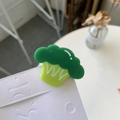 Detail view of a cute acrylic broccoli hair clip with glossy green finish on white board - Broccoli
