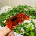 Gros plan sur une pince à cheveux en forme d'hippopotame ambré avec détails orange - Hippopotame