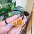 Detailopname van een gele harsstrik op een bruine haarwokkels met hoge elasticiteit - Jelly Oranje