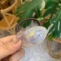 Detail view of the elastic hair tie featuring a tortoiseshell resin charm and logo - Triangular Oval Hair Rope / White Mermaid