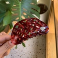 Dettaglio ravvicinato della pinza per capelli rosso scuro con logo in metallo dorato - Rosso (Pinza a Maglia Vuota)