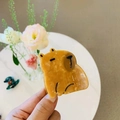 Detailed view of a caramel acetate capybara hair claw clip held in hand with floral decor - Calm Capybara