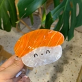 Schattige zalm sushi haarklem met cartoon rijstbal gezicht en oranje vis textuur - Sushi-stijl