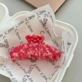 Detalle macro de pinza de pelo grande de acetato con textura de mármol rosa y resorte - Rojo Sandía