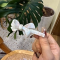 Detailopname van witte acetaat strik haarklem met elegante parelmoer glans afwerking - Witte Bloemenstrik