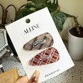 Détail des barrettes à carreaux rouges et verts avec strass et logo sur le support - Style Plaid Gris Rouge Strass Texte
