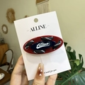 Oval hair clip with red frame and navy blue woven rope detail on a brand card - Red Base Black Rope