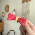 Close-up of pink and yellow bow-shaped hair clip made of glossy resin with a metal base - Pink