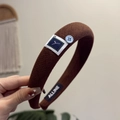 Detail van de bruine geribbelde hoofdband met vierkante patch, blauwe knoop en merklabel - Donkere Koffie Retro Hoofdband