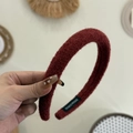 Détail de la texture d'un bandeau en peluche rouge foncé avec étiquette faite main - Rouge