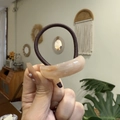 Detail of high-elasticity dark brown hair tie with a beige resin decor piece and SANSHINE engraving - Ellipse / Buttercream