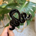 Dettaglio della molletta per capelli nera a forma di serpente con finitura lucida su foglie - Nero Lucido