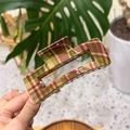 Dettaglio macro di una grande pinza per capelli a scacchi rossi e verdi con finitura lucida - Plaid Rosso Verde - Quadrato
