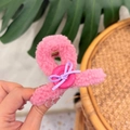 Nahaufnahme der flauschigen Teddy-Haarklammer in Pink mit Knopf und lila Schleife - Rosenrosa