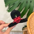 Detail showing plush black teddy hair claw clip with red velvet bow and button accent - Black