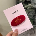 Macro shot of red velvet hair clip with gold firework embroidery on festive card - Red Velvet Oval Firework Duck Hair Clip