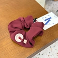 Deep burgundy fabric scrunchie with button detail and logo tag on wooden surface - Hair Tie / Red Button Knot Scrunchie