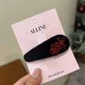 Detail shot of a black velvet hair clip with red abstract embroidery on a display card - Black Velvet Red Firecracker Duck Hair Clip