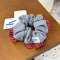 Détail d'un chouchou à rayures rouges avec étiquette de marque sur bois - Chouchou Bleu Gris Bordure Sergé Rouge
