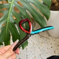Detail of a wavy black hair claw clip with colorful oil drip accents and sturdy grip teeth - Blue Red Chocolate Patchwork Hanger Style