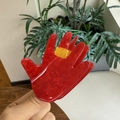 Macro shot of a red palm-shaped acrylic hair claw with yellow accent details - Fortune Palm Style