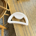 Detail view of a cream semi-circular hair claw clip on a minimalist wooden table surface - Light Nude Pink