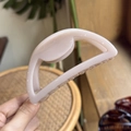 Detail showing a 10cm pale pink semi-circular matte hair claw clip held by hand - 10cm / Light Nude Pink