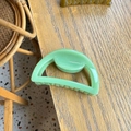 Detail view of 7cm Morandi green semi-circular hair claw clip on a natural wooden table - Leaf Green