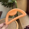 Macro detail of a 10cm peach orange hollow hair claw clip with smooth acrylic finish - 10cm / Bright Orange