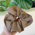 Close-up of a brown checkered scrunchie with soft cotton texture and elastic pleats - Brown