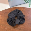 Detail of a black plaid scrunchie with pleated texture on a rustic wooden table surface - Black