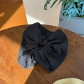 Close-up of black oversized scrunchie with subtle plaid texture on wooden surface - Black