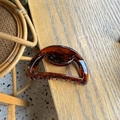 Detailed view of an amber acrylic shark hair clip with a semi-circle hollow design - Glossy Red Brown
