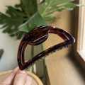 Detail of 10cm amber tortoiseshell claw clip held by hand showing size and resin gloss - 10cm / Glossy Red Brown