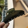Close-up of a large translucent dark grey acetate hair claw clip with fine golden glitter detail - Transparent-Dark Green