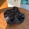 Macro detail of glossy black satin scrunchie with Miniline label on wooden background - Black Brown