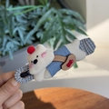 Gros plan d'une pince à cheveux ours polaire en peluche avec détails en tissu rayé - Chien Blanc Allongé Pince