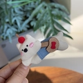 Close-up of cute plush puppy hair claw with denim outfit and pink blush details - Laying White Dog Duckbill Clip